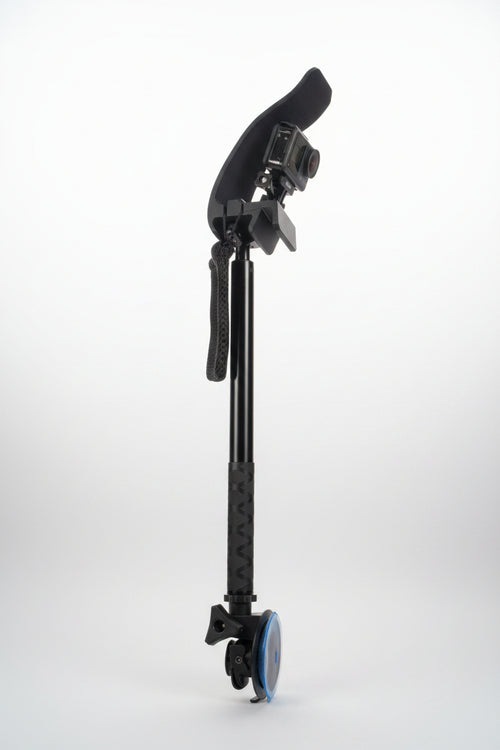 A black and gray camera rig with a suction cup, mounting bracket, and textured handle grip, photographed on a gray fabric background.